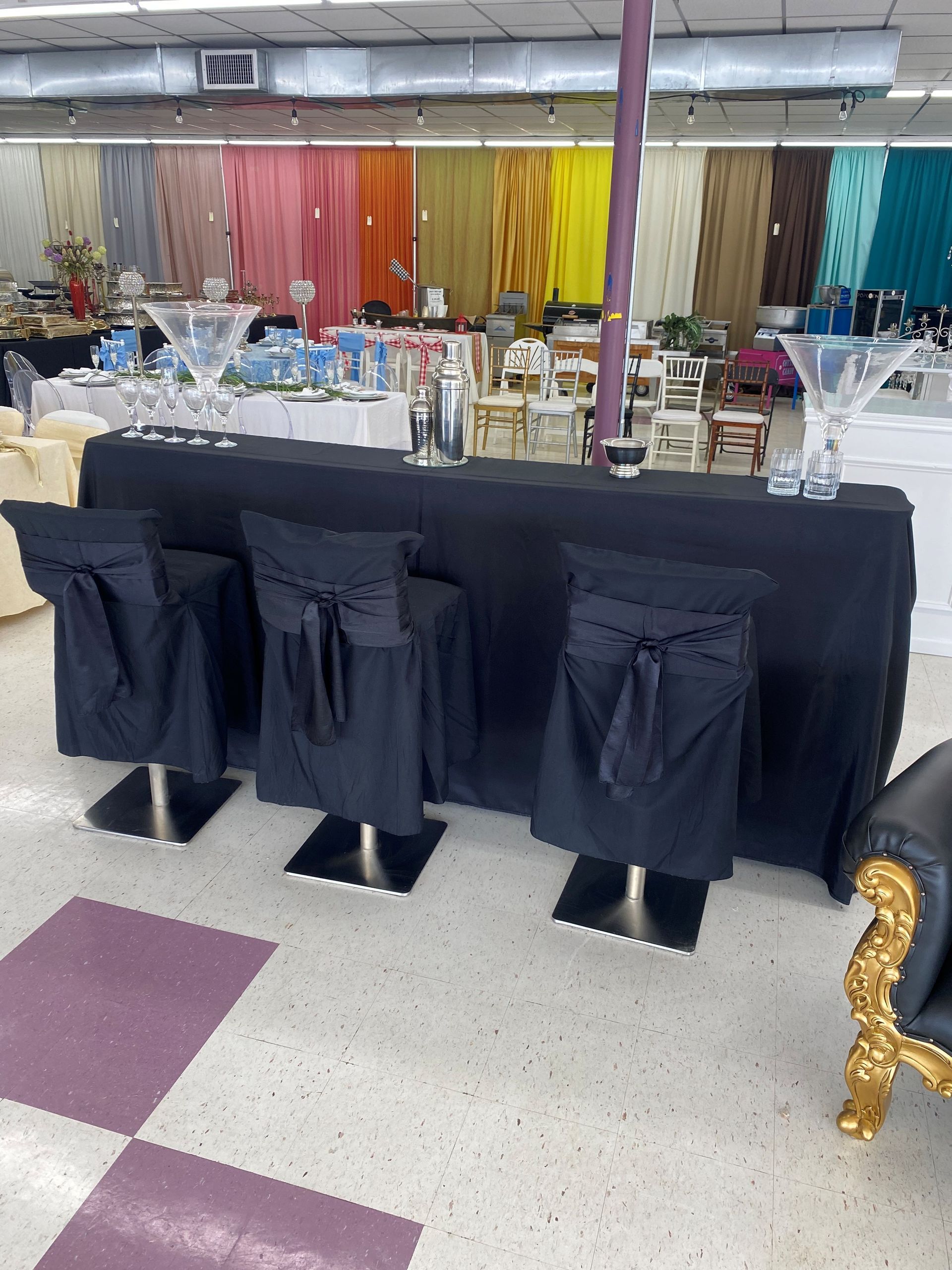 A long wedding reception table set with gold linen napkins, woven chargers, tapered candles, and rustic floral centerpieces.