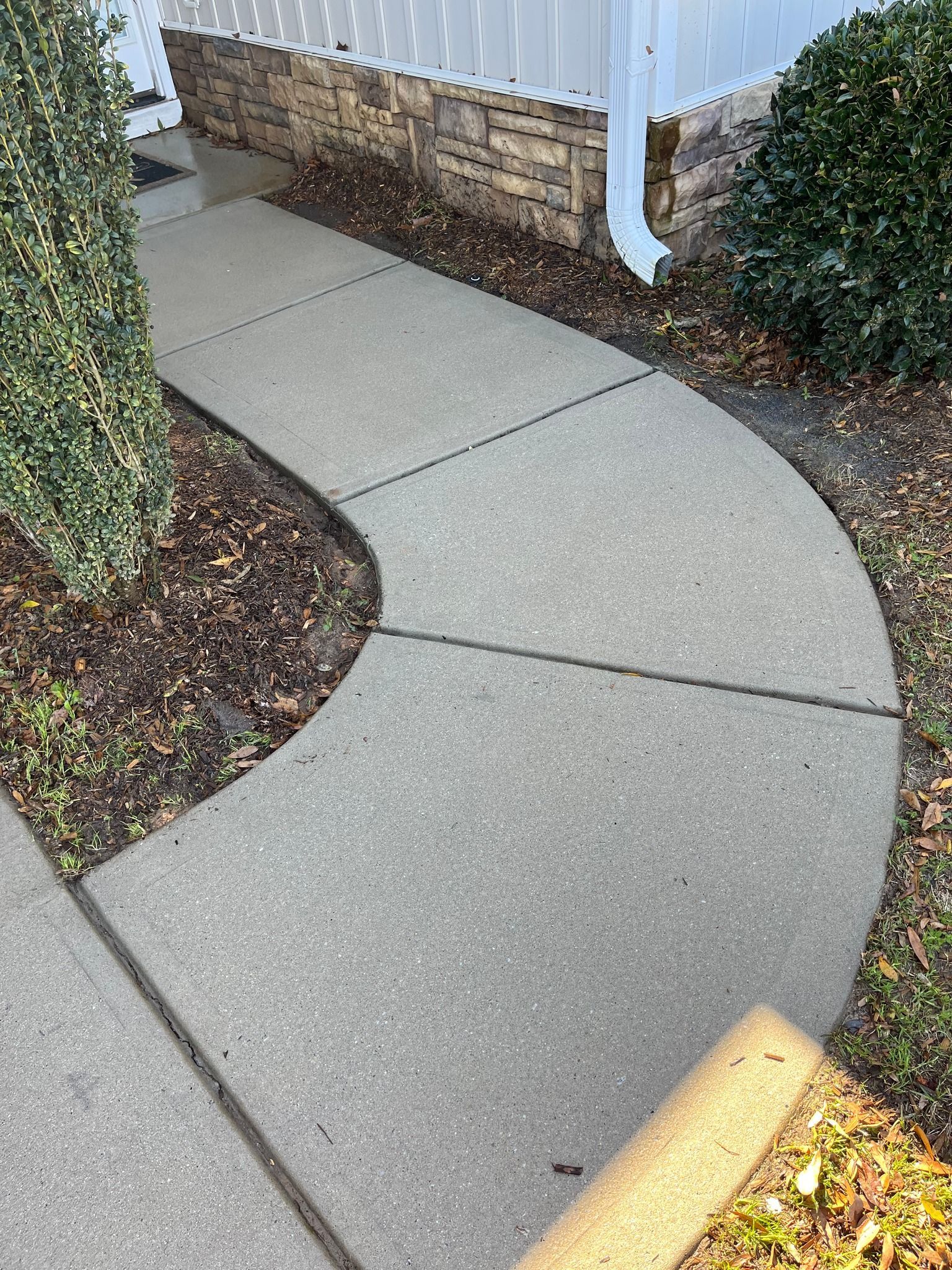A curved concrete walkway leading to a house.