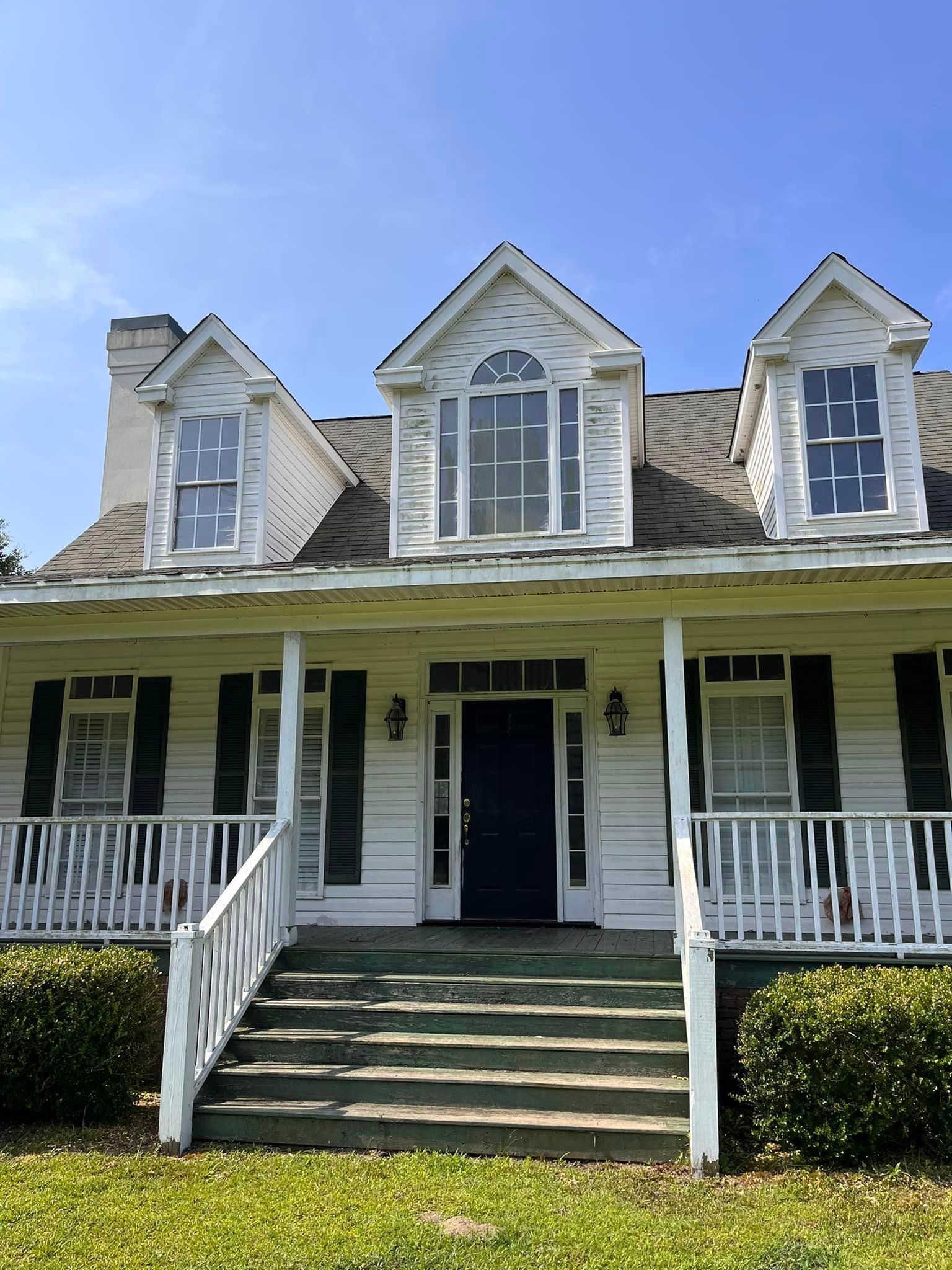 A white house with black shutters and stairs