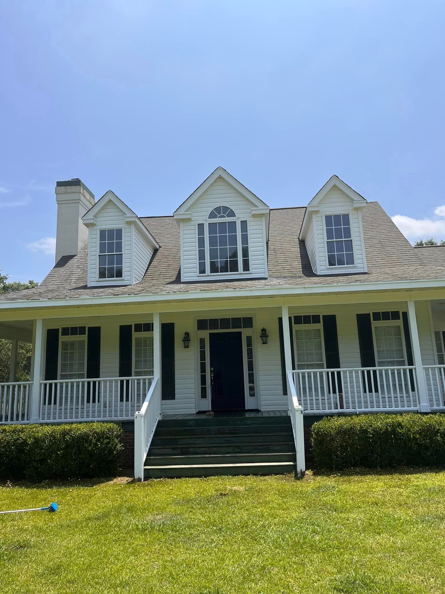 A large white house with black shutters and a large porch.