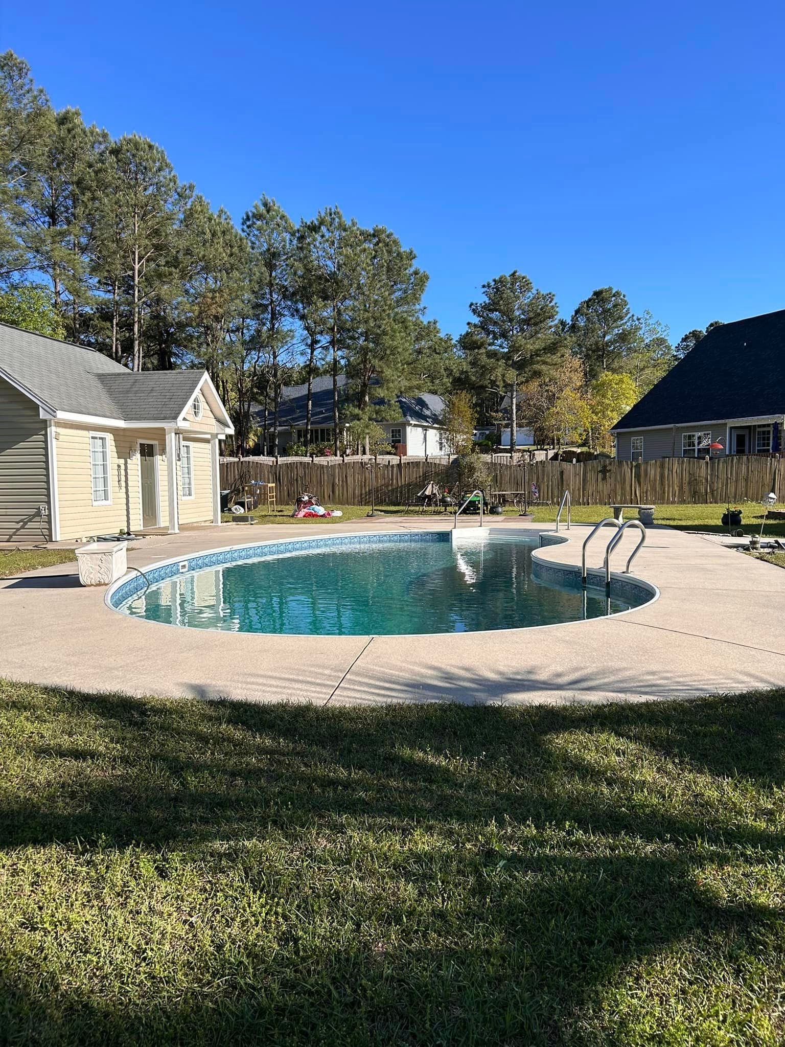 A large swimming pool is in the backyard of a house.