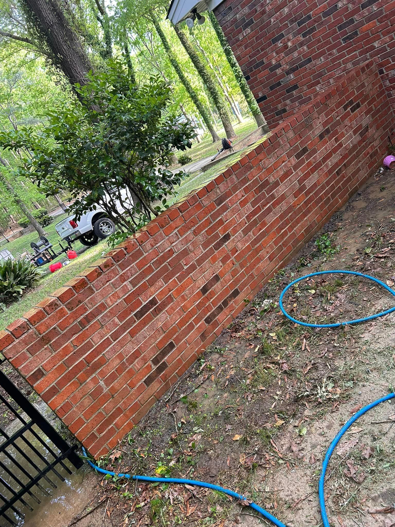 A brick wall with a blue hose attached to it.