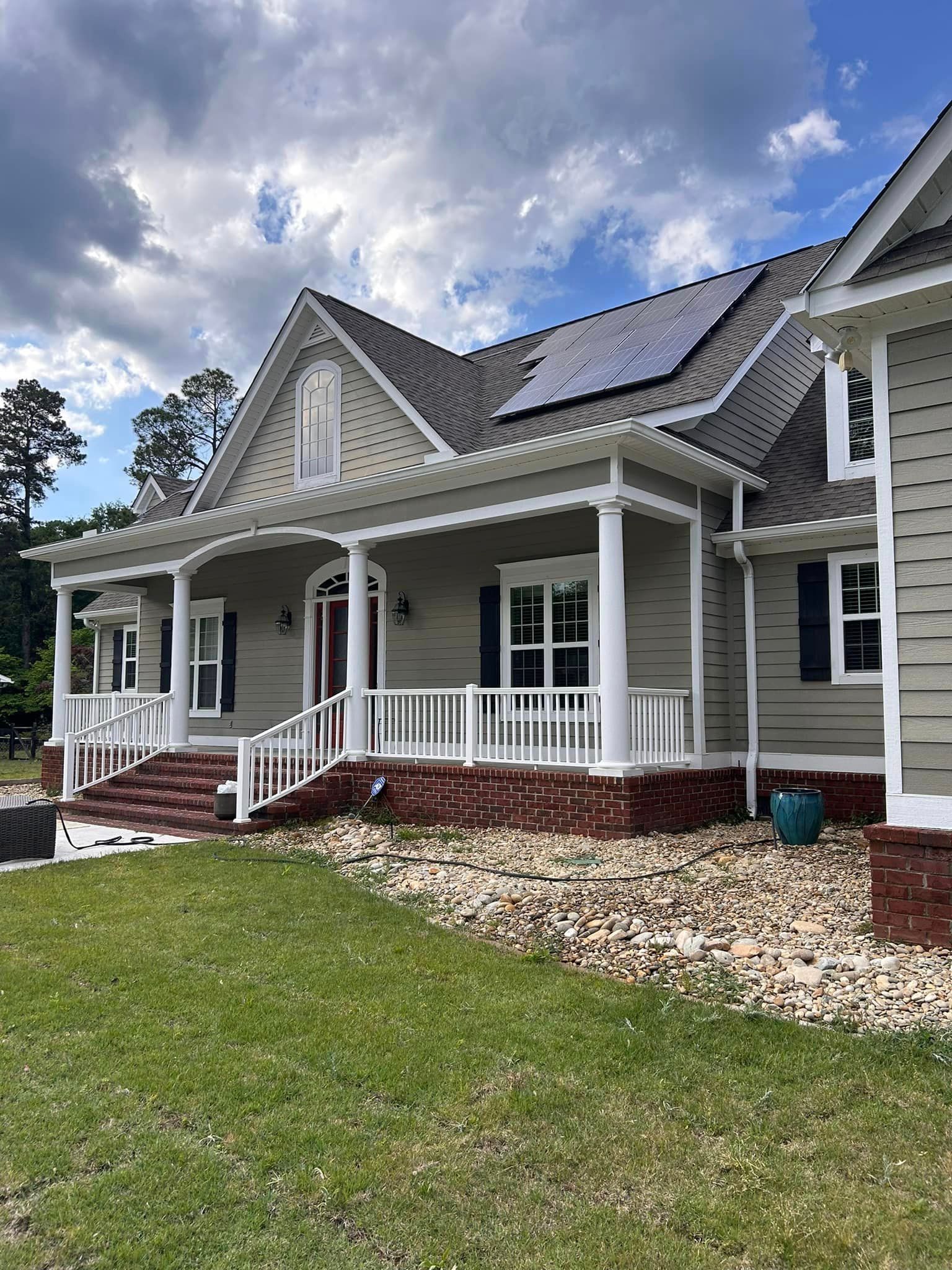 A large house with a porch and solar panels on the roof.