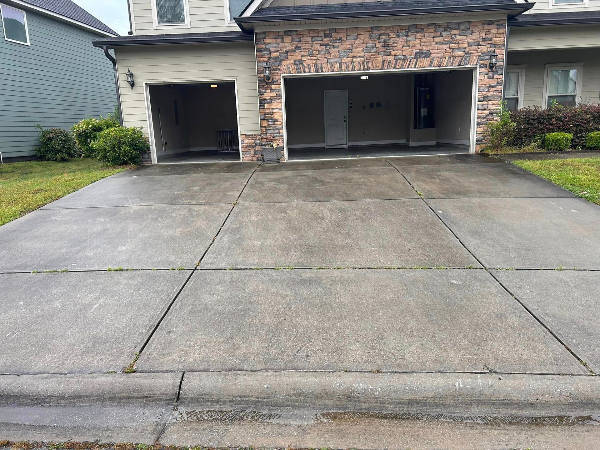 A concrete driveway in front of a house with two garages.