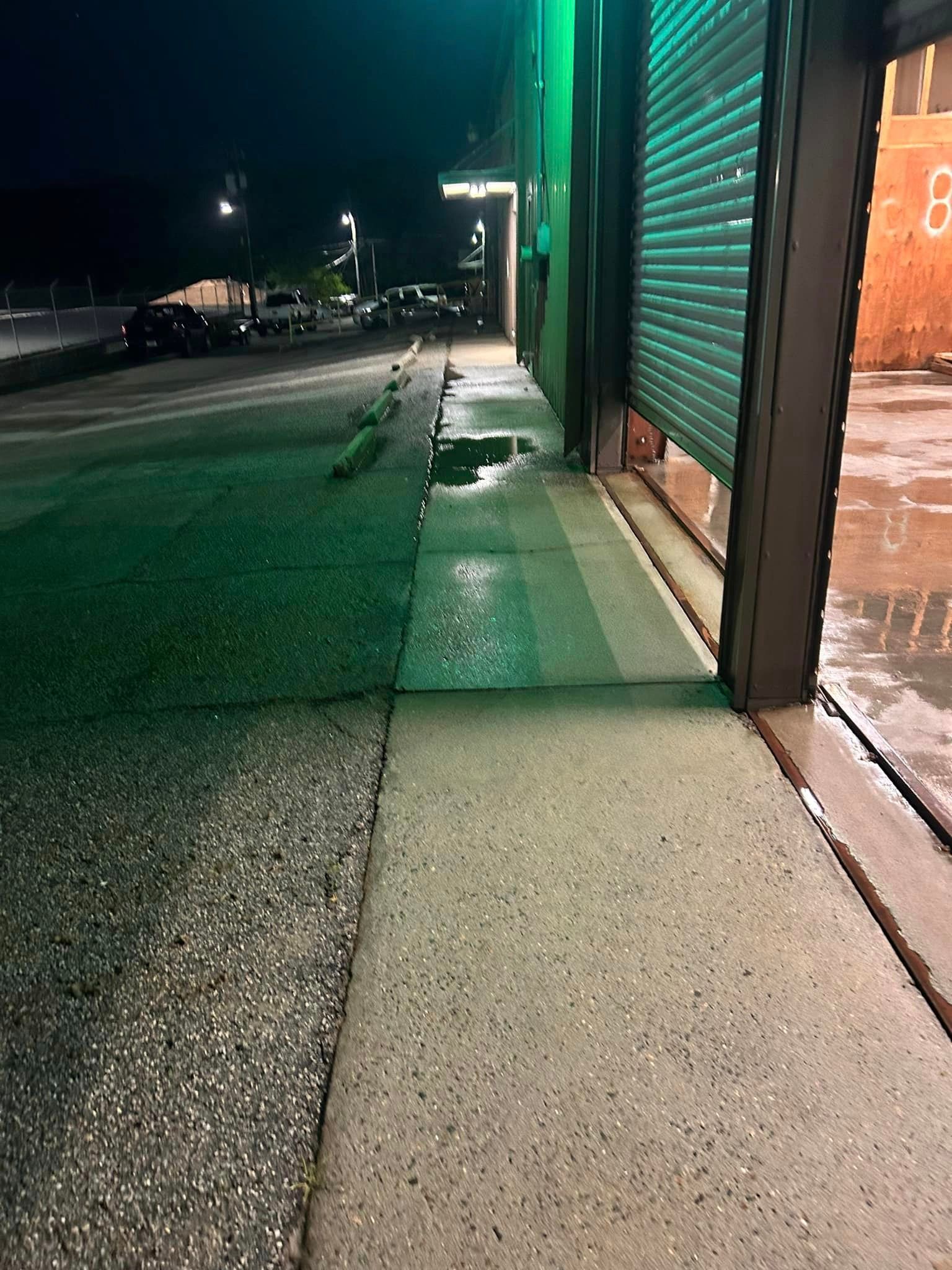 A sidewalk next to a building with a green garage door