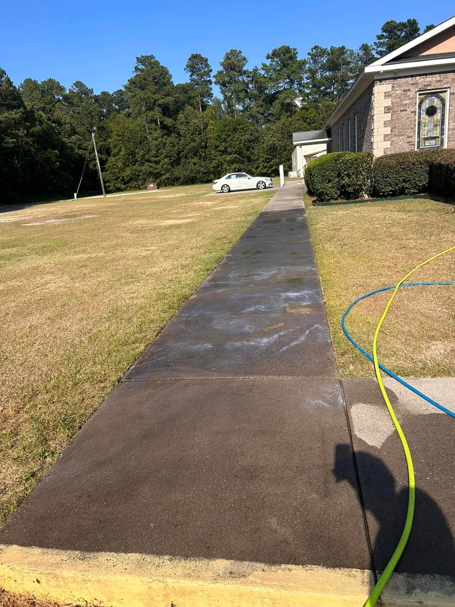 A hose is being used to clean a sidewalk in front of a house
