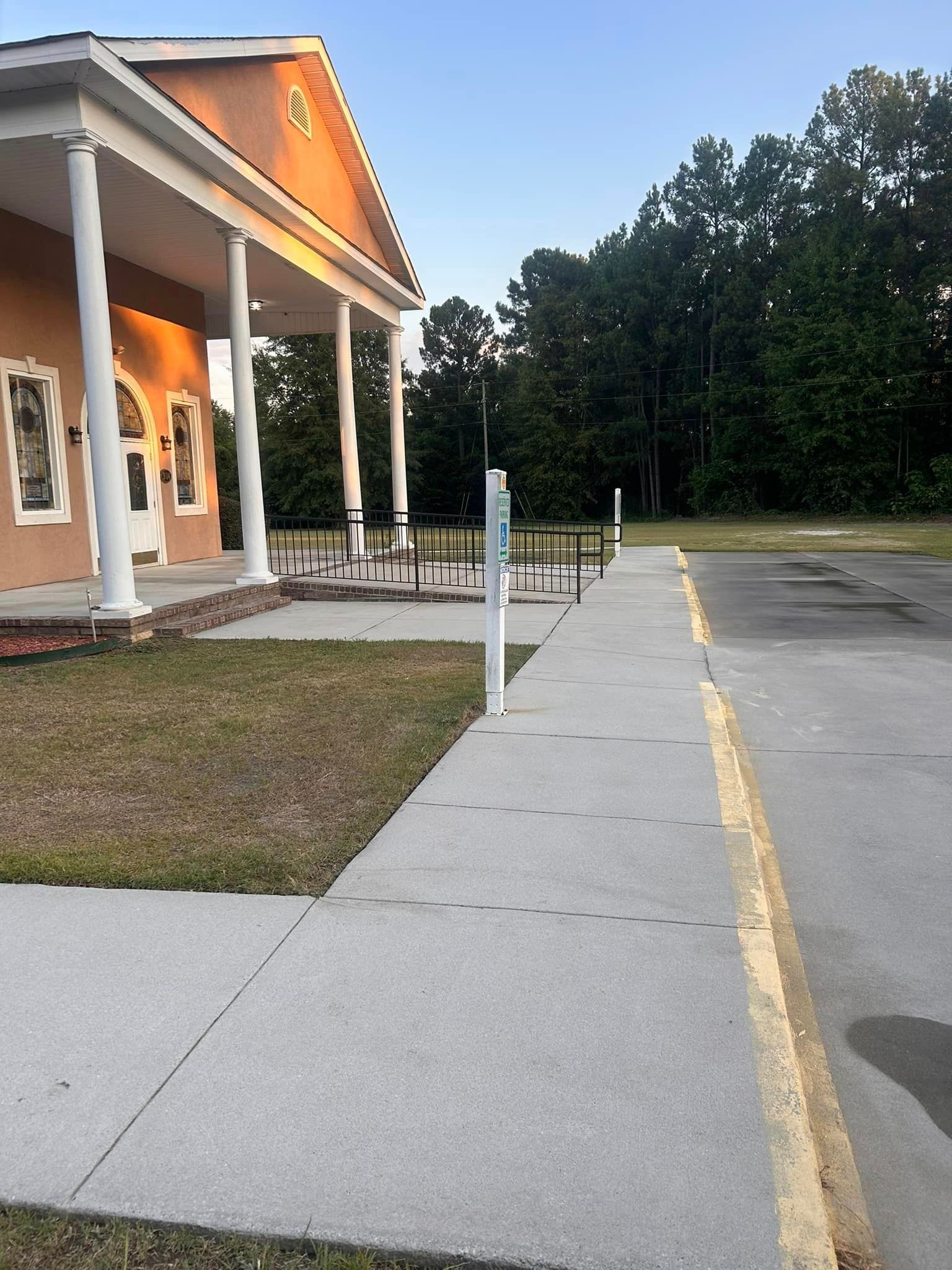 A concrete walkway leading to a building with columns