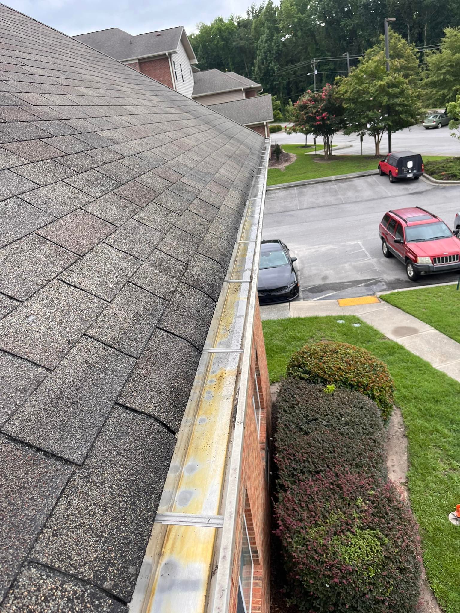 A gutter on the side of a building next to a parking lot.