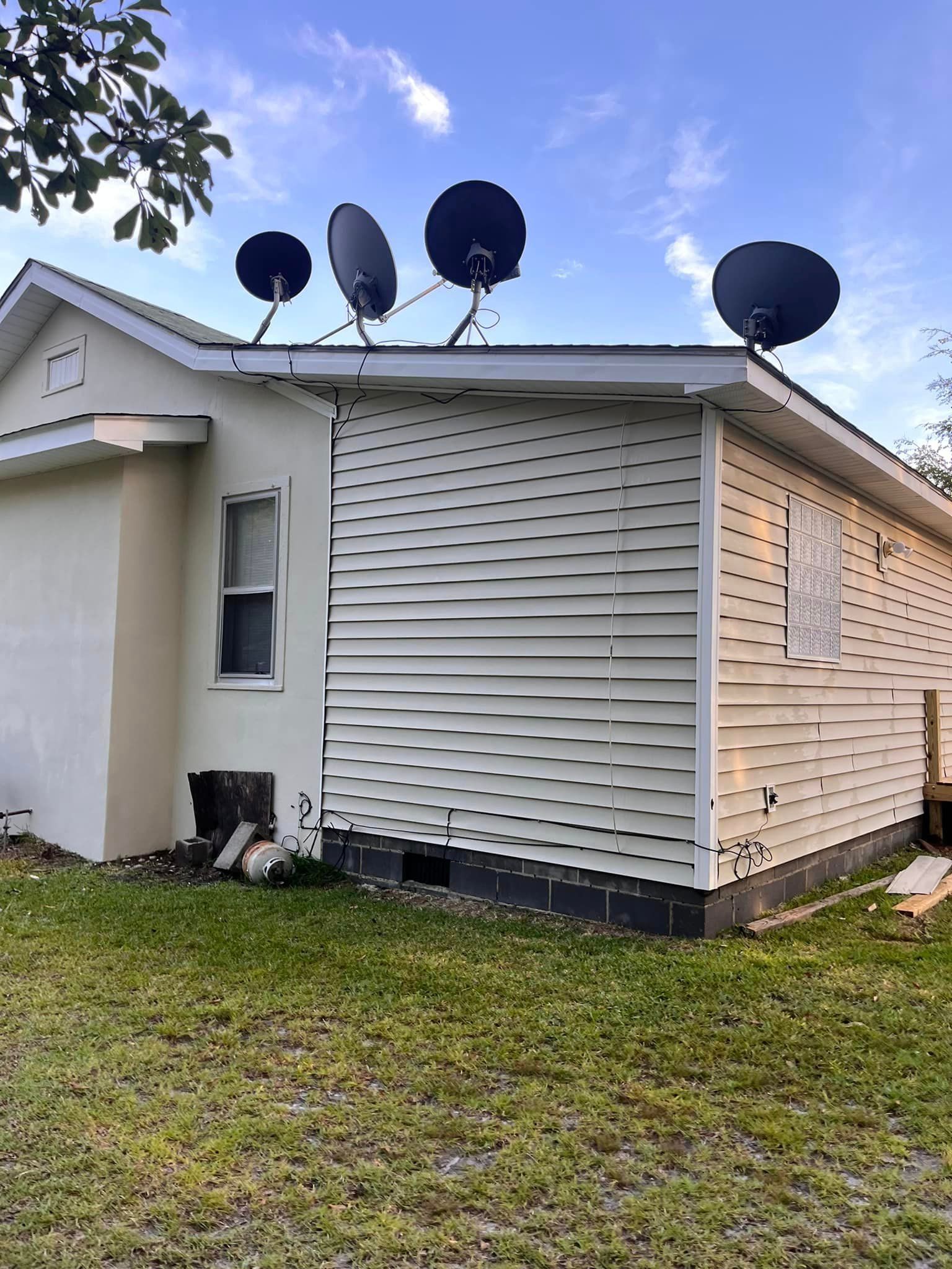 A white house with satellite dishes on the roof.