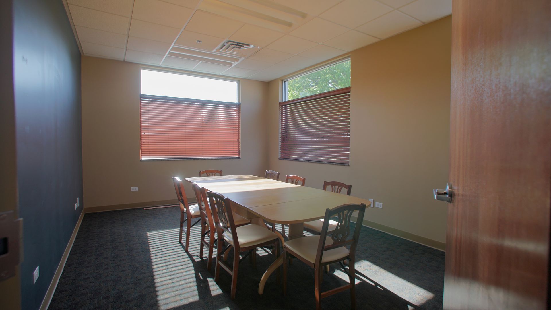 Small conference room with a table, chairs, and two windows with blinds.