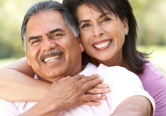 Smiling couple embracing outdoors in bright sunlight