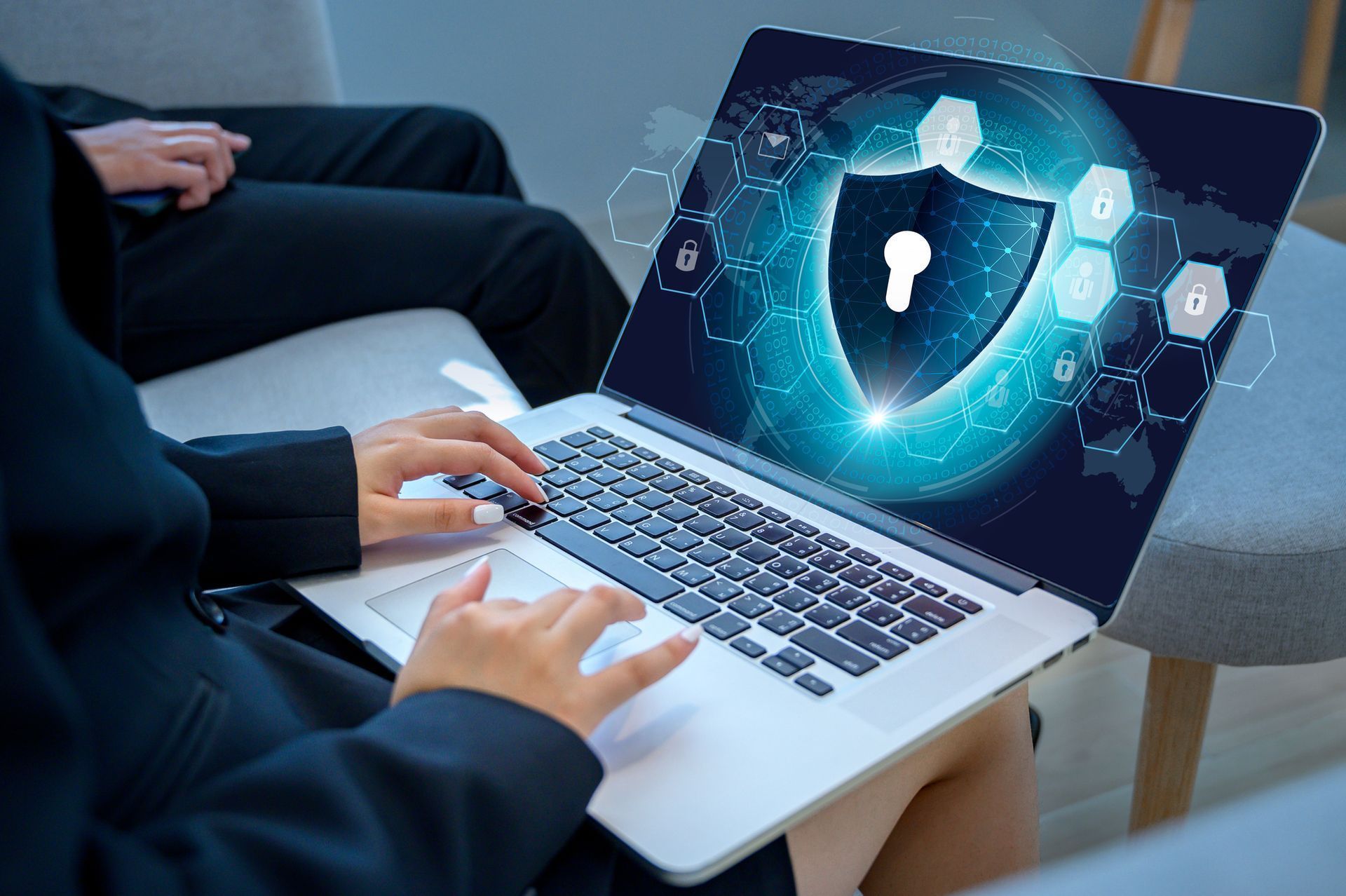 A person is typing on a laptop computer with a shield on the screen.