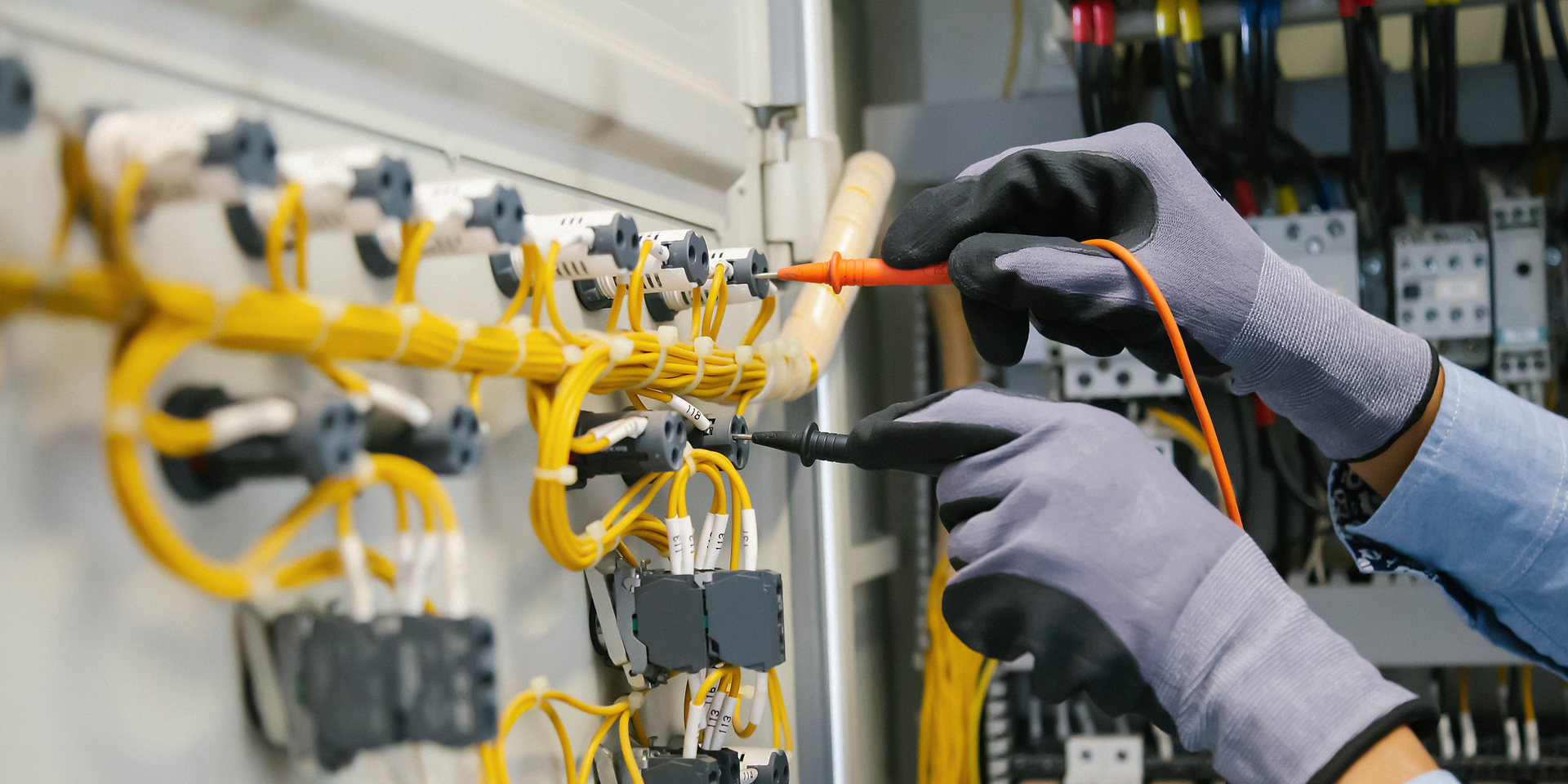 A person is working on an electrical panel with a screwdriver.
