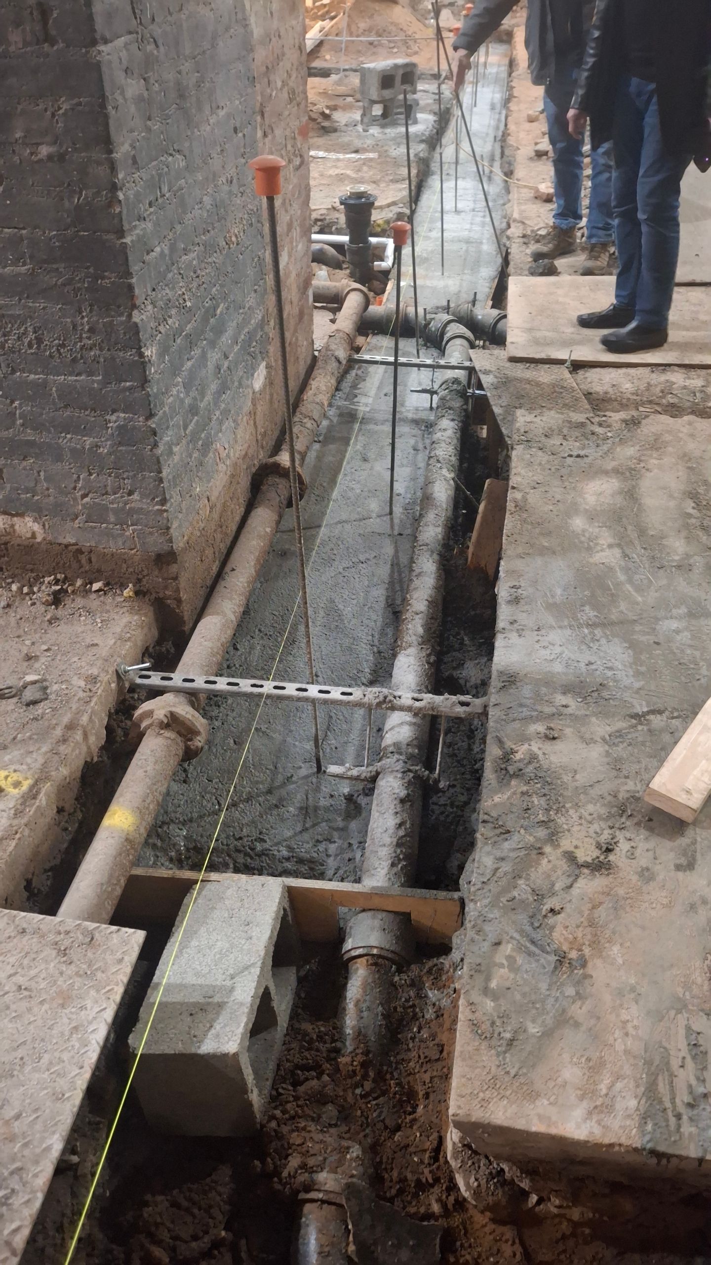 A group of men are standing next to a pipe in the dirt.
