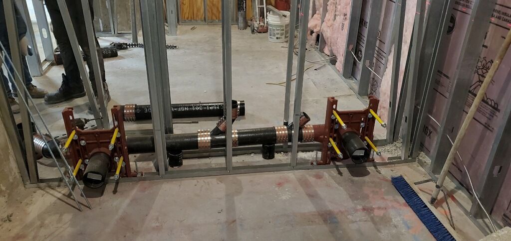 A building under construction with a lot of pipes on the floor.