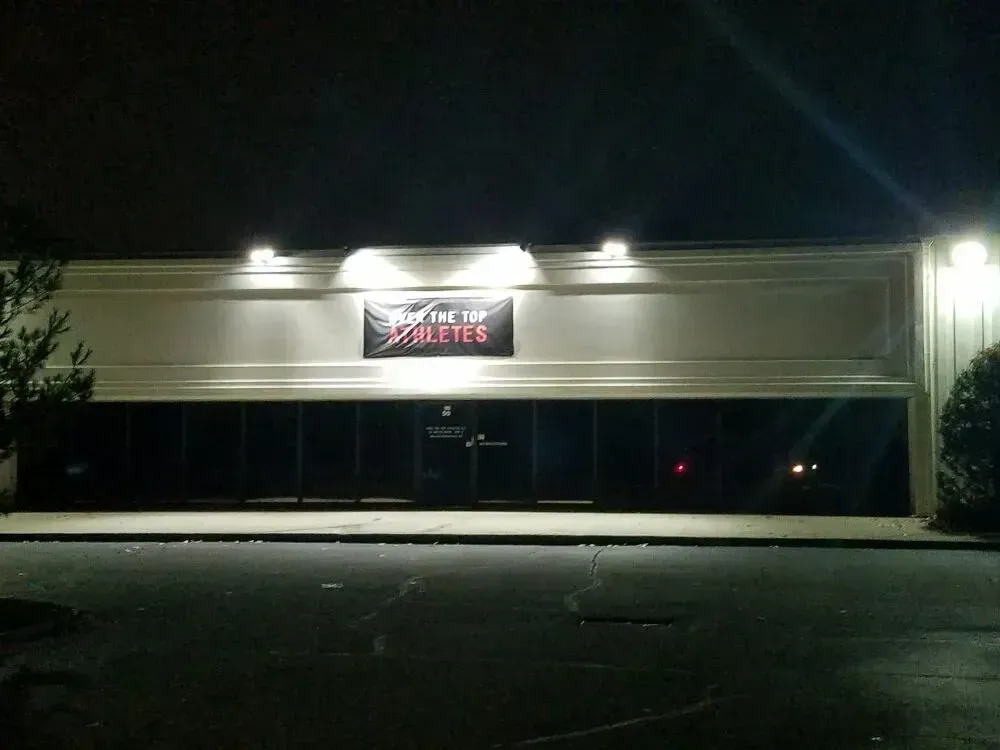 A dark night view of a strip mall storefront with a sign that reads