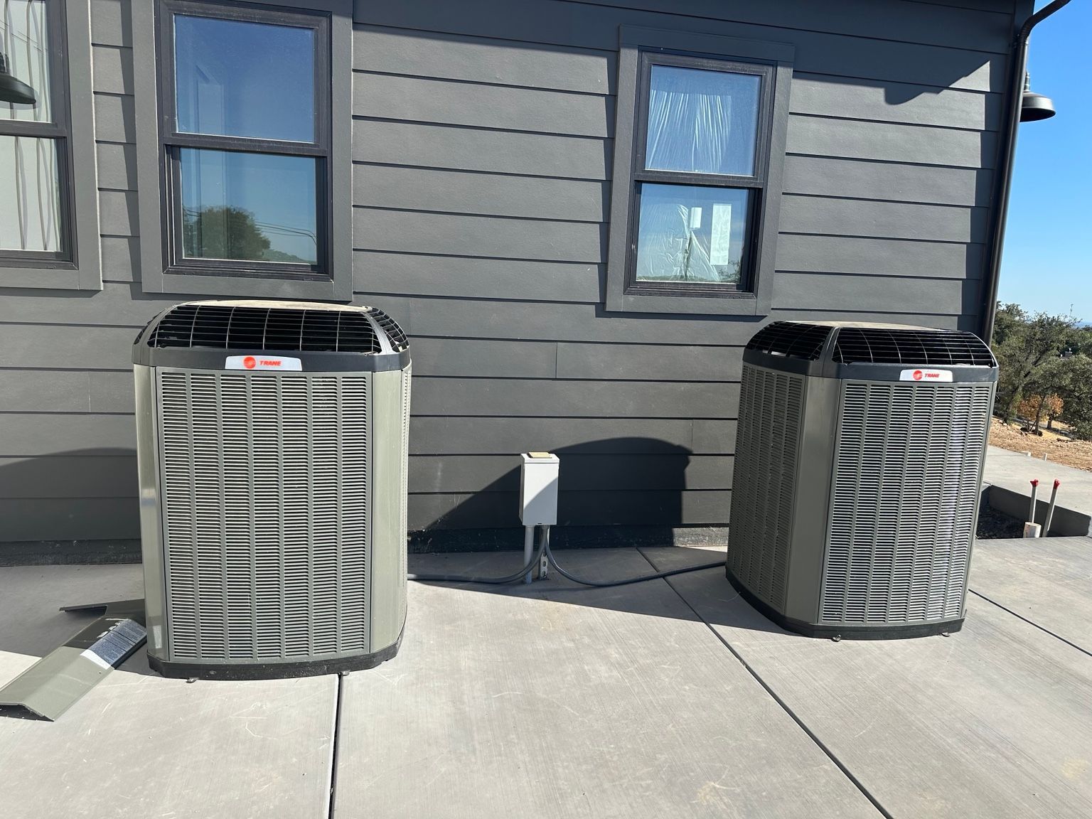 Two outdoor condensers installed on a concrete pad beside the building