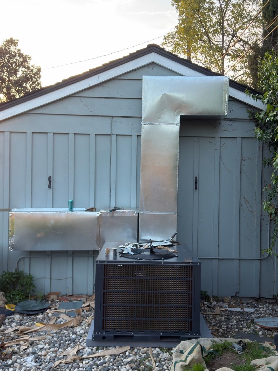 Custom rectangular ductwork extending from an outdoor HVAC unit along the building wall