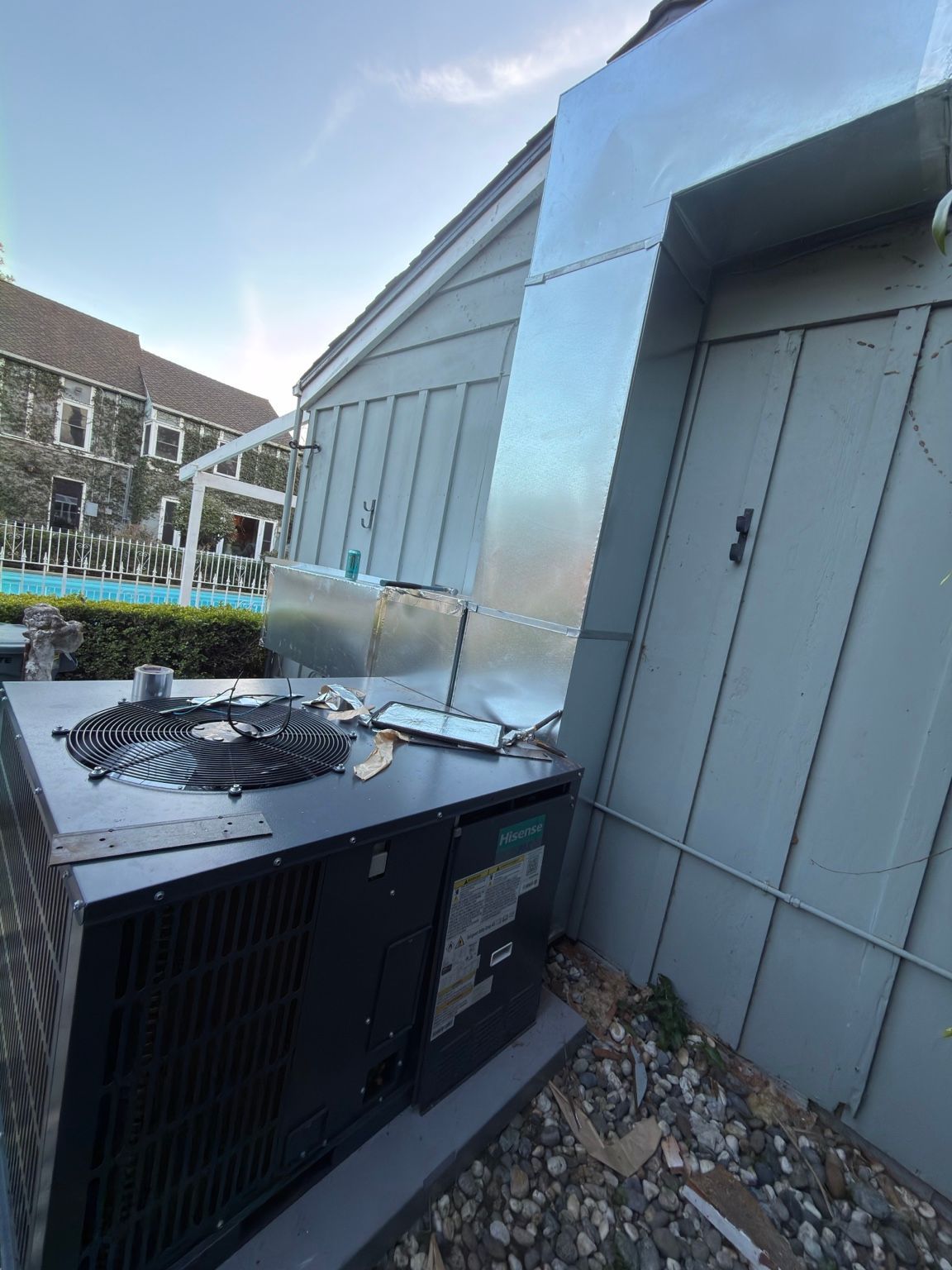 Side view of custom sheet-metal ductwork connecting outdoor HVAC equipment to the building