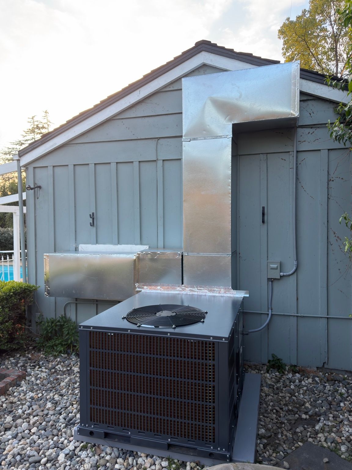 Completed sheet-metal duct connection behind the outdoor HVAC unit
