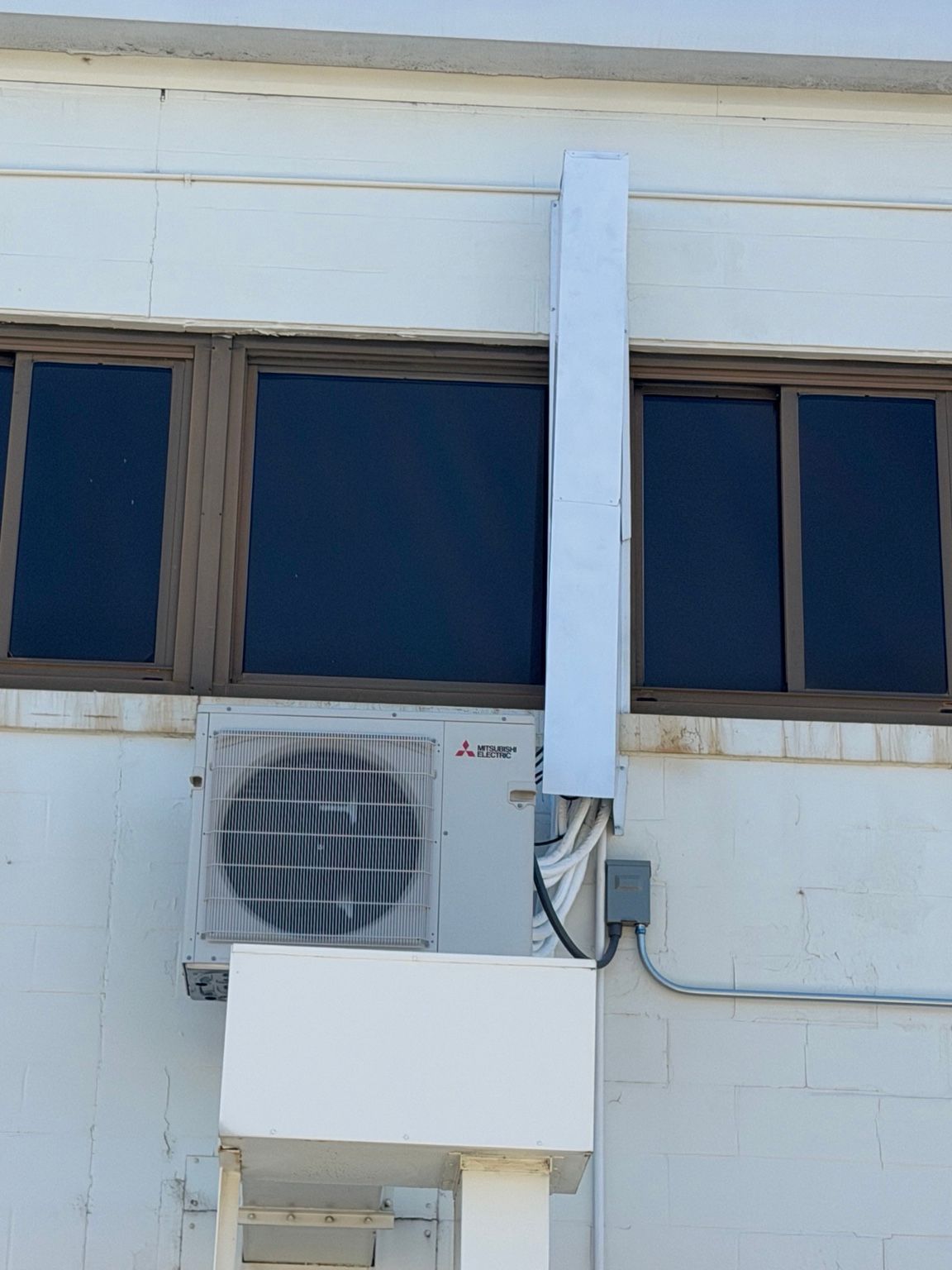 Outdoor HVAC unit and line cover beneath the building windows