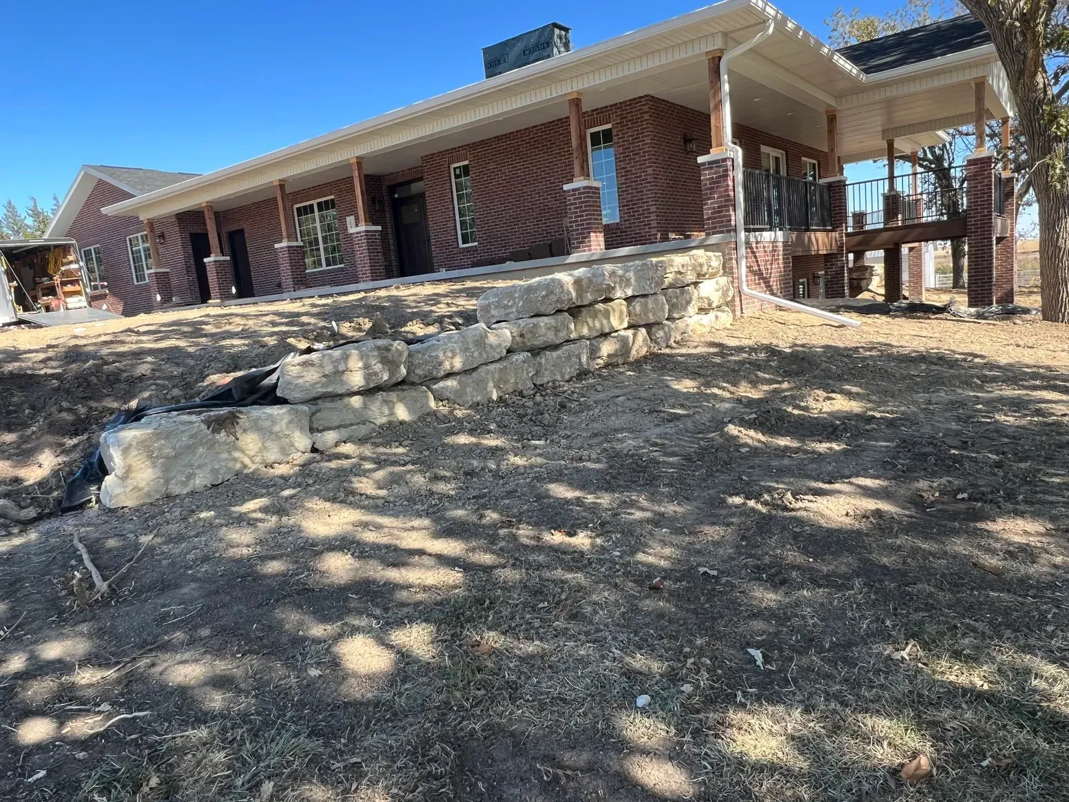 A Large Brick House with A Stone Wall in Front of It — Exeter, NE — Axline Landscaping & Trees