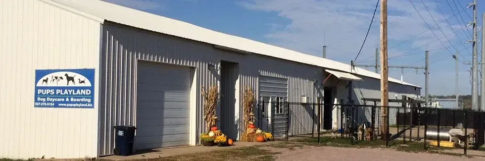 Industrial warehouse exterior with a metal building, blue sign, and flames near an open bay door