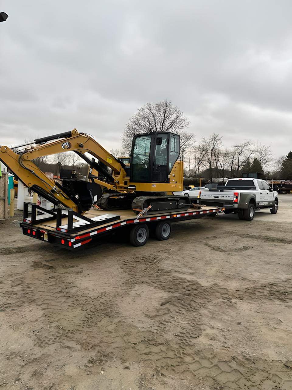 A truck is towing a yellow excavator on a trailer