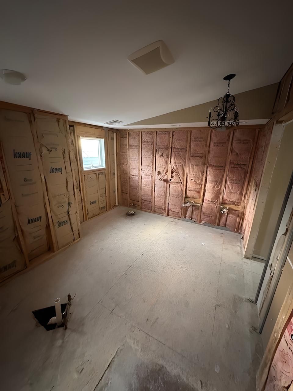 A room with a lot of insulation on the walls and a chandelier hanging from the ceiling