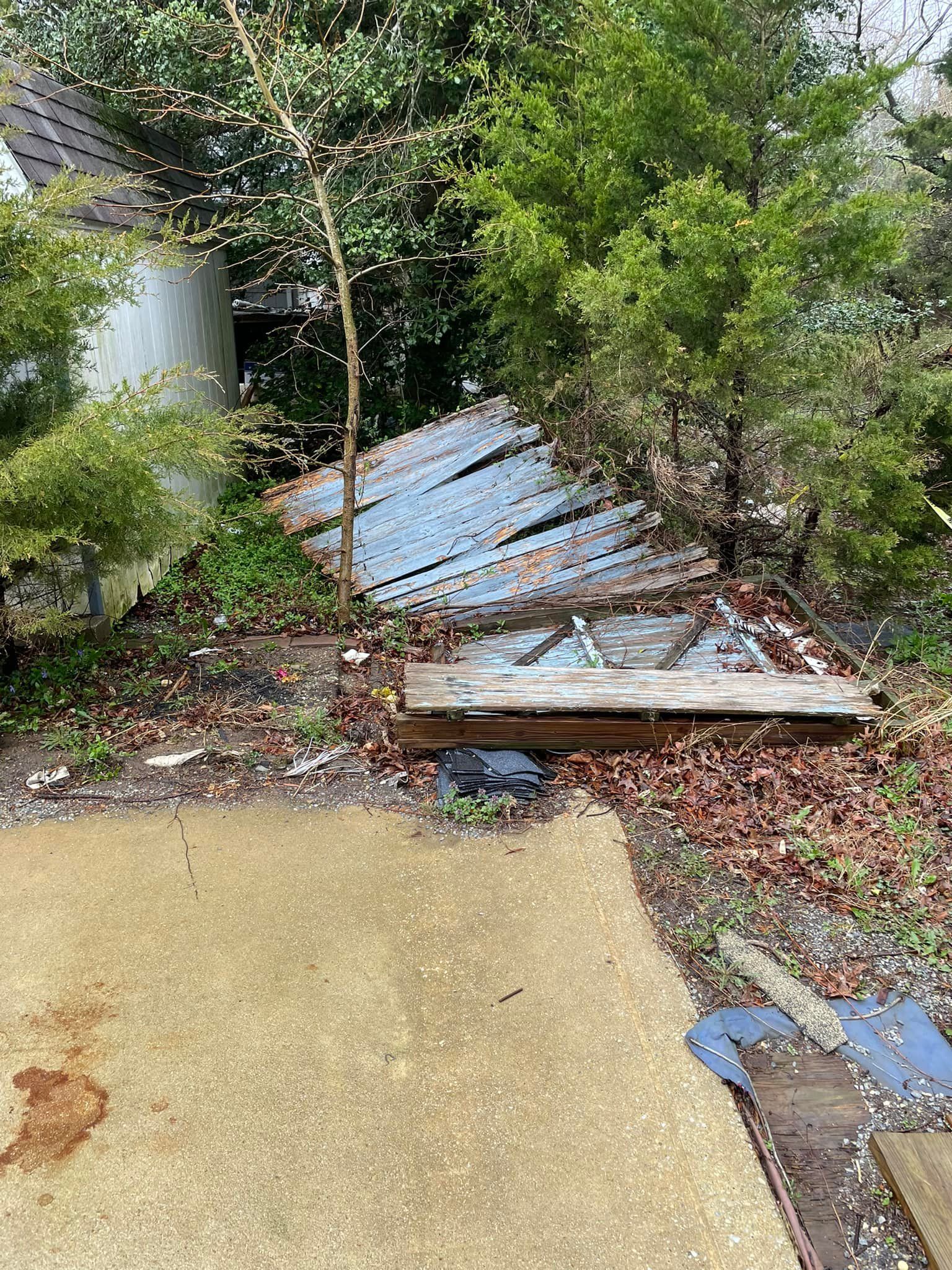 A wooden plank is sitting on the ground in a yard surrounded by trees