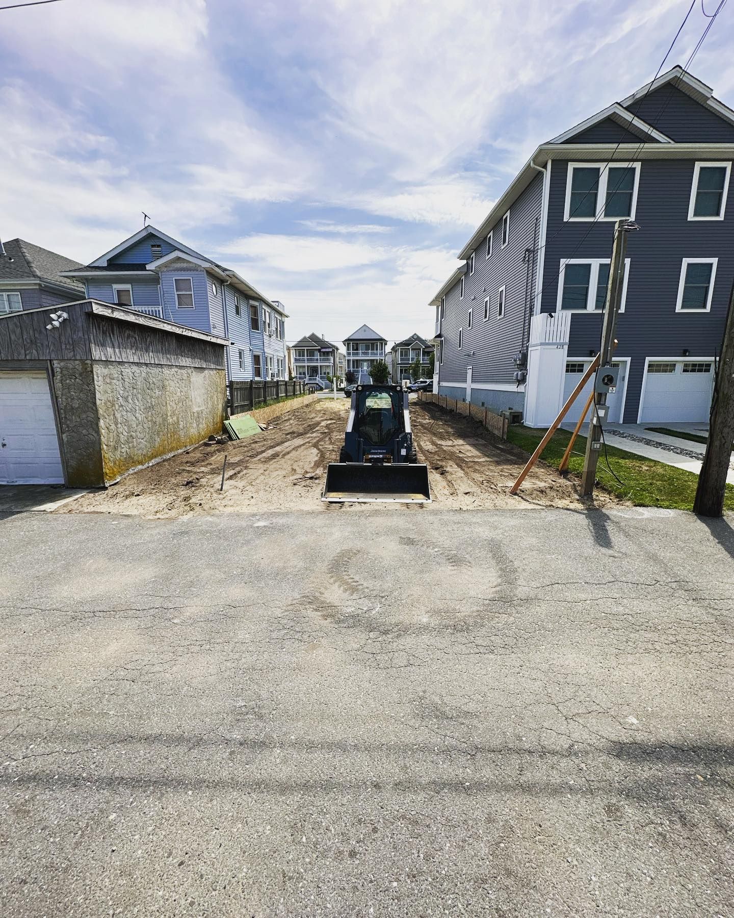 A bulldozer is driving down a dirt road between two houses
