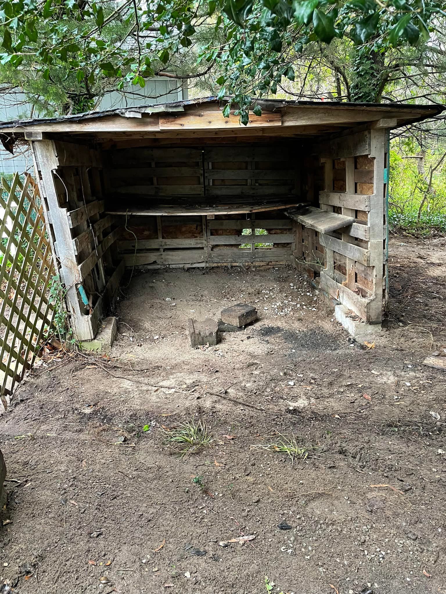 A wooden shed is sitting in the middle of a dirt field
