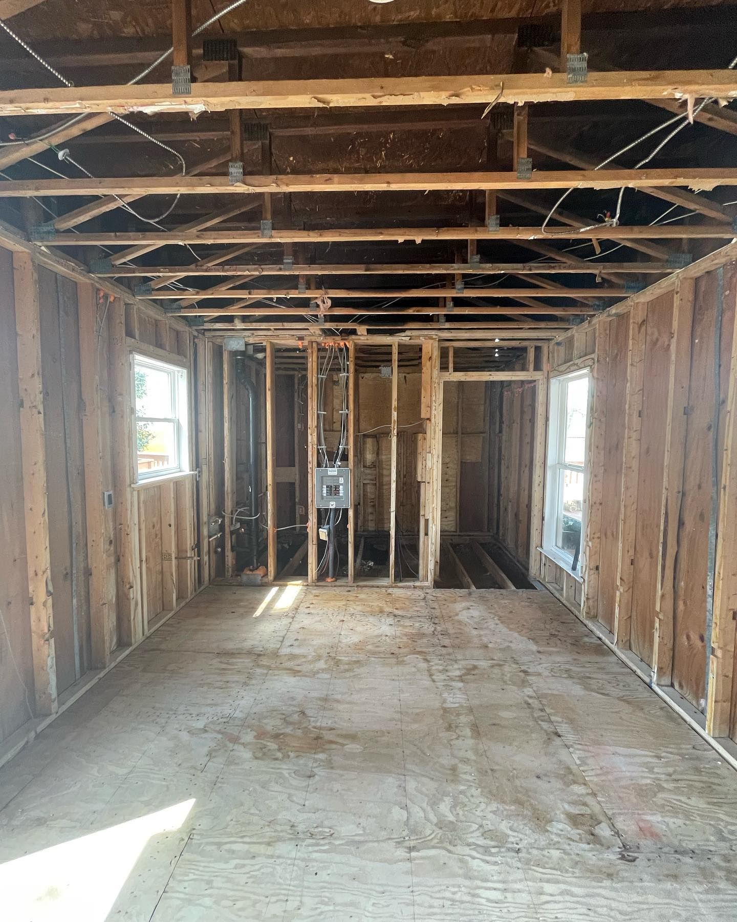 The inside of a house under construction with wooden beams and windows