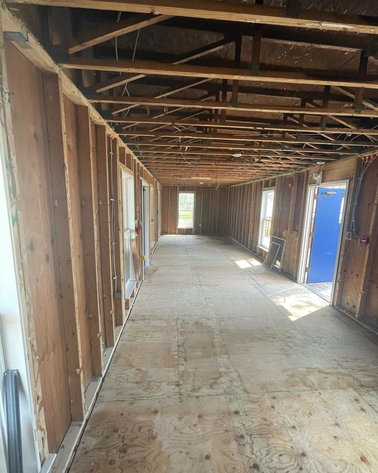 A long hallway with wooden beams and a blue door