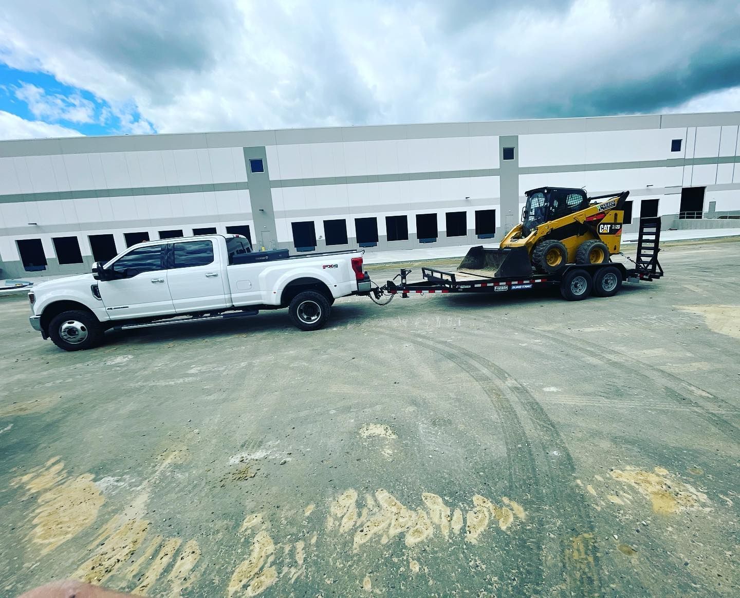 A white truck is towing a yellow bulldozer on a trailer