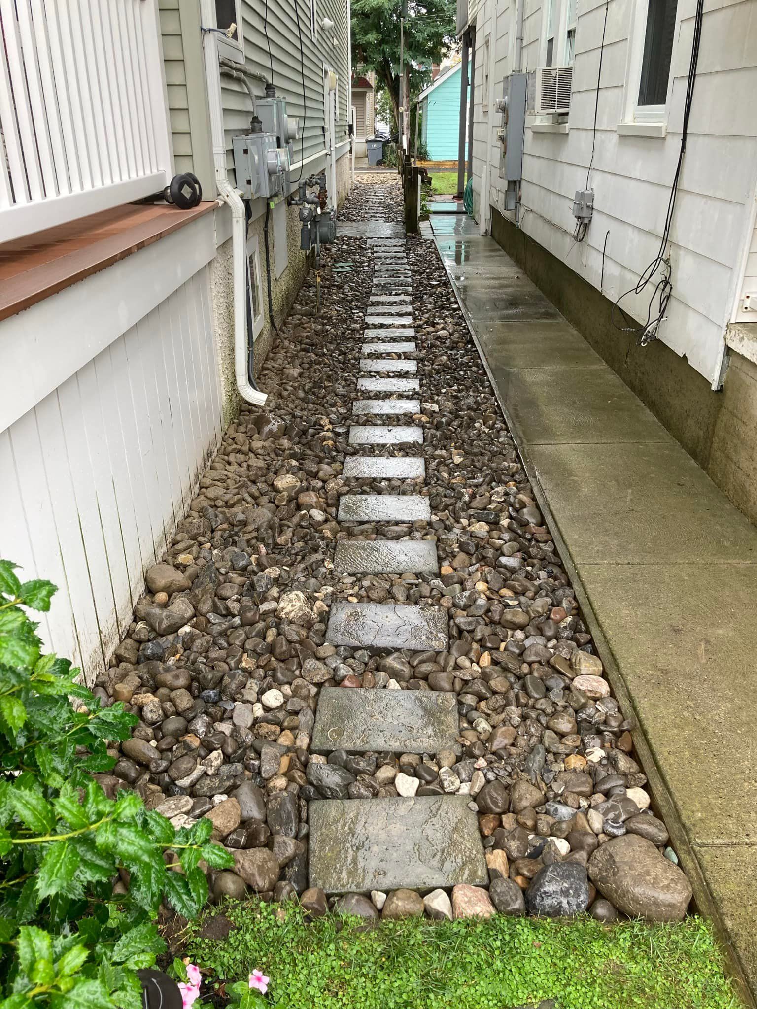 A stone walkway between two houses in the rain