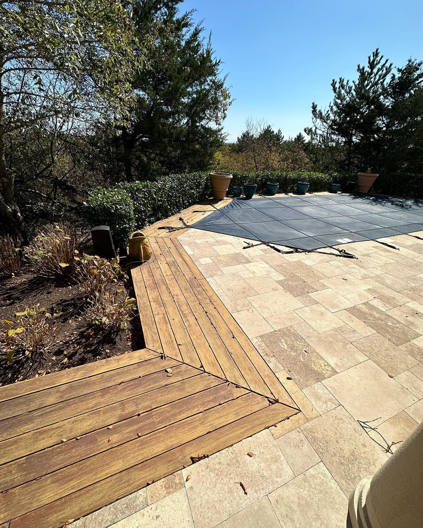 A wooden deck with a swimming pool in the background