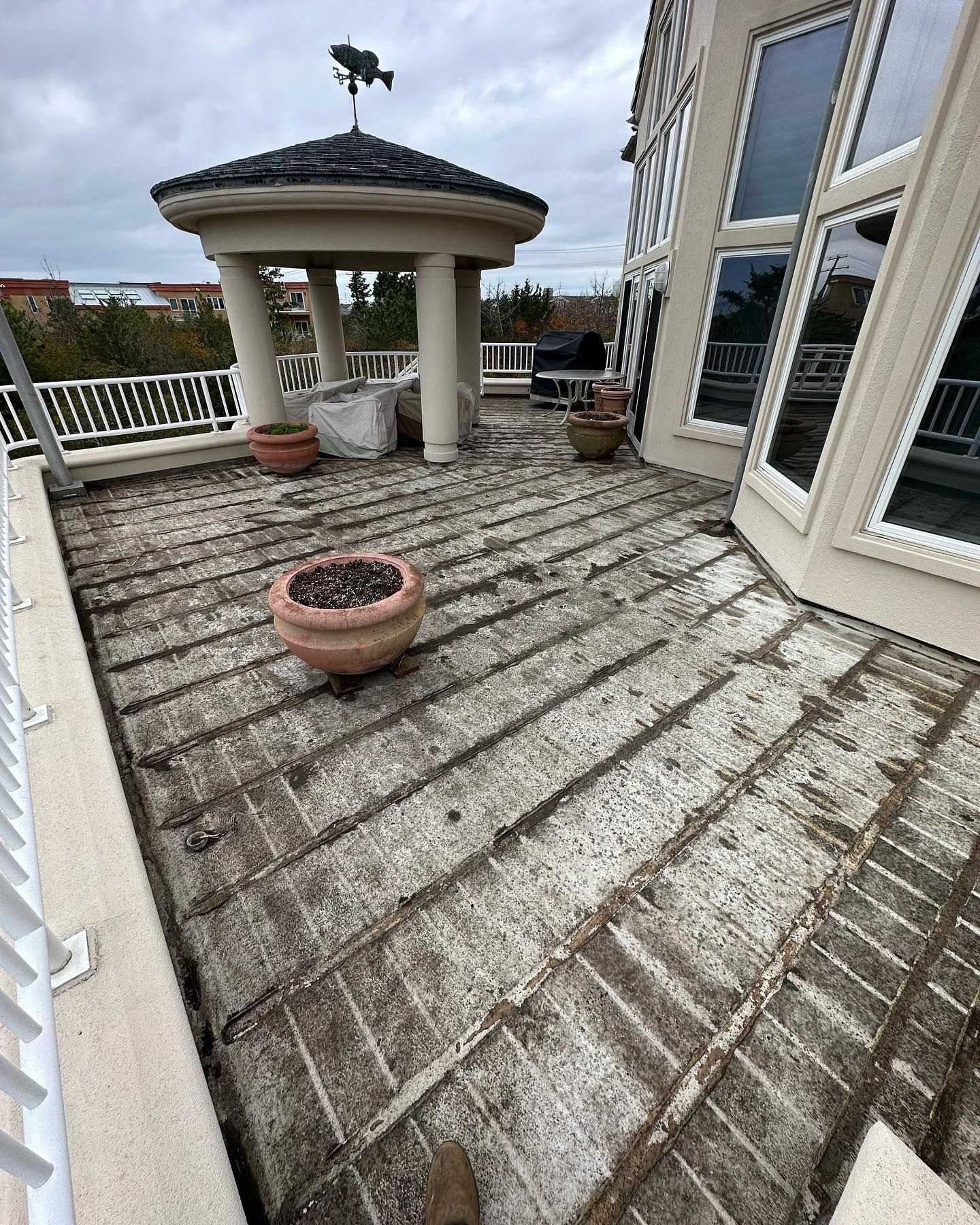 A dirty deck with potted plants and a gazebo on top of it