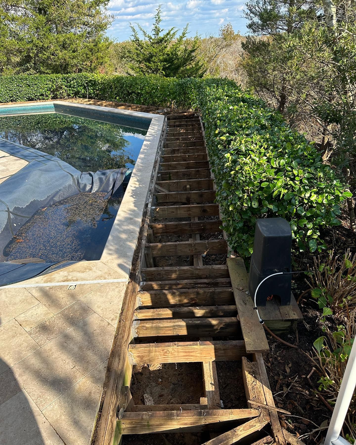 A wooden deck is being removed next to a pool
