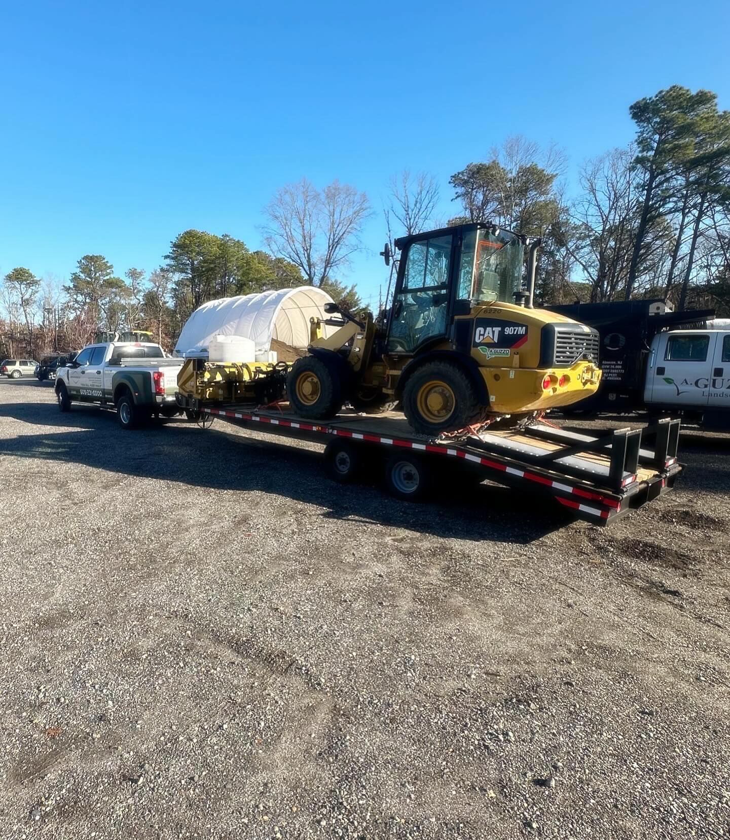 A truck is towing a tractor on a trailer