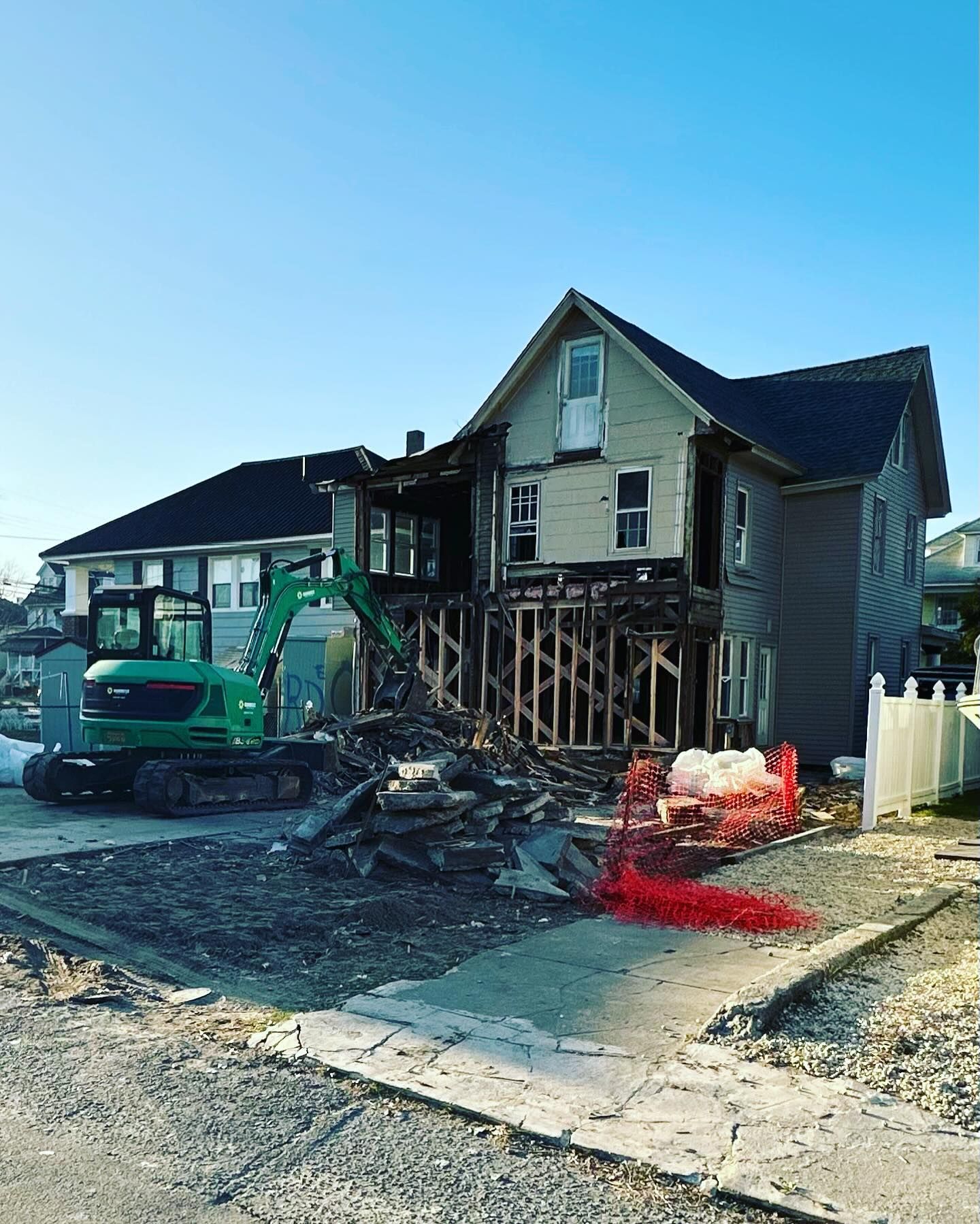 A house is being demolished by a green excavator