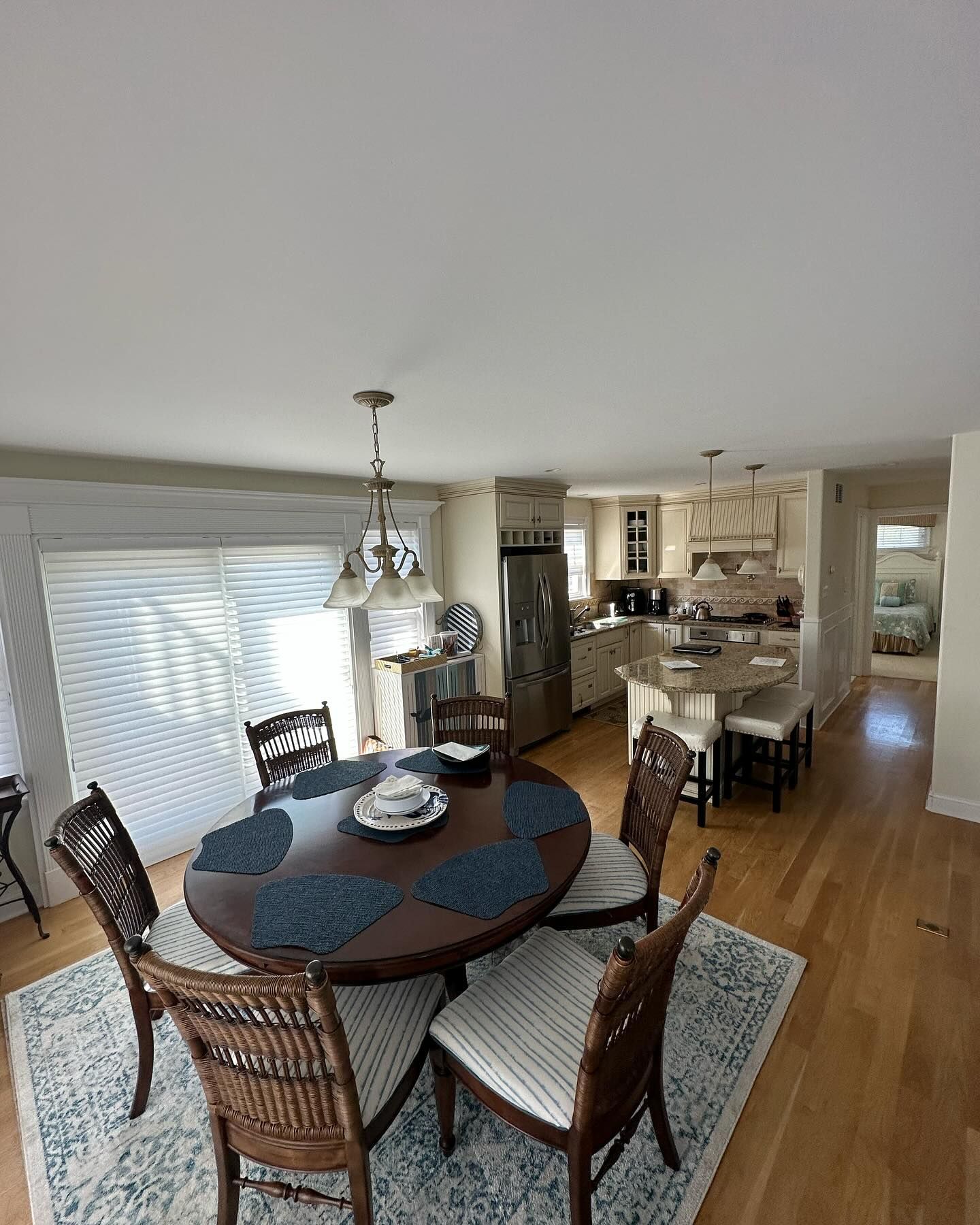 A dining room with a round table and wicker chairs