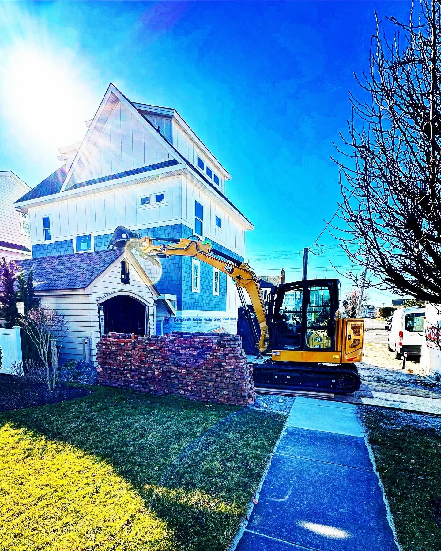 A house is being demolished by a yellow excavator