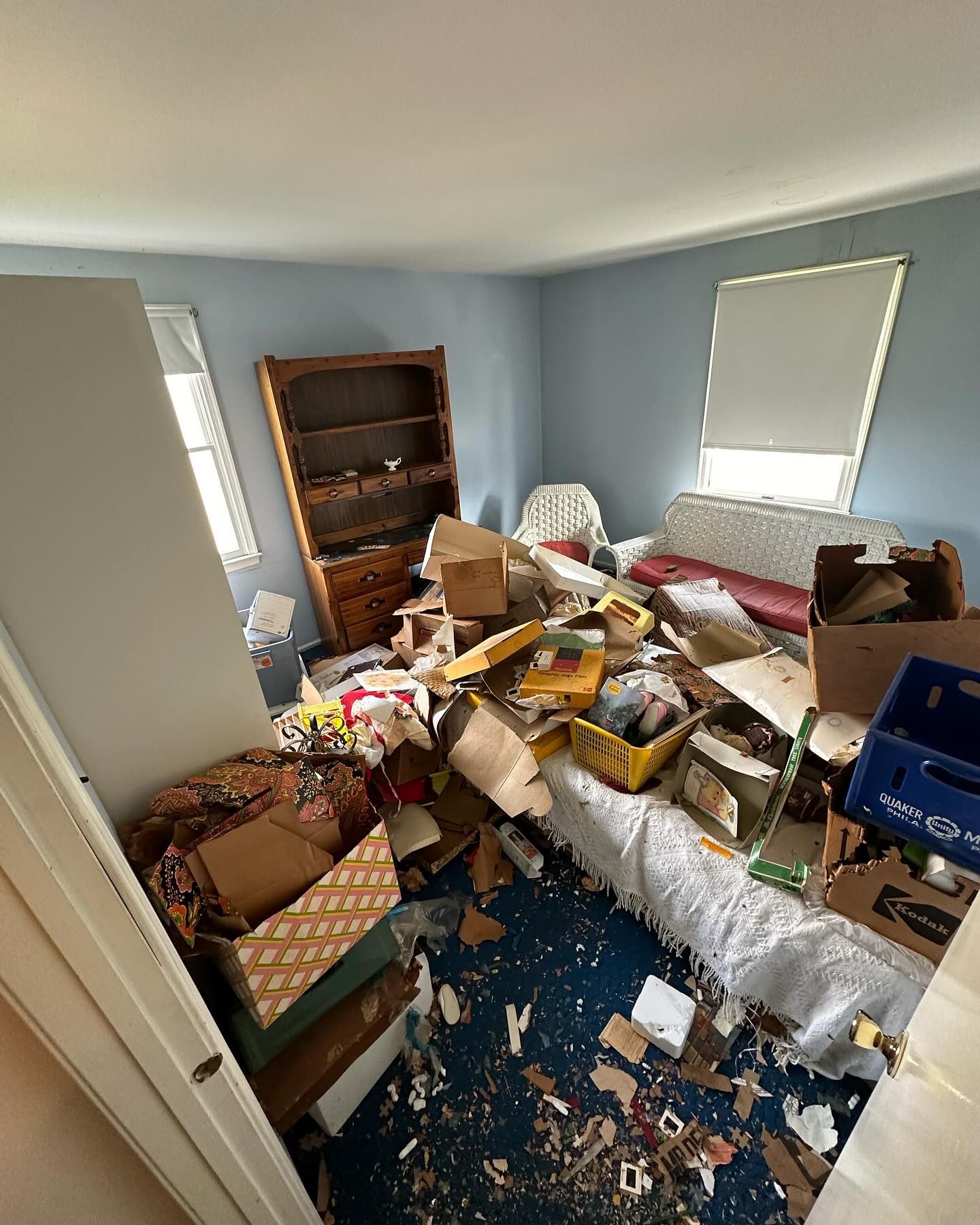 A bedroom with a bed, dresser, bookshelf, and boxes on the floor