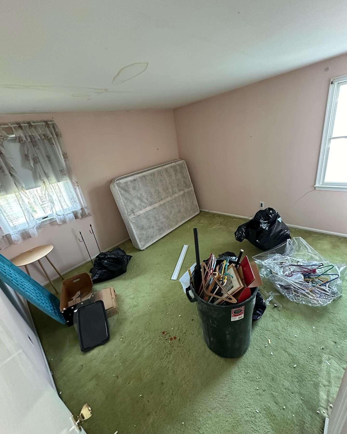 A room with a mattress and a trash can in it