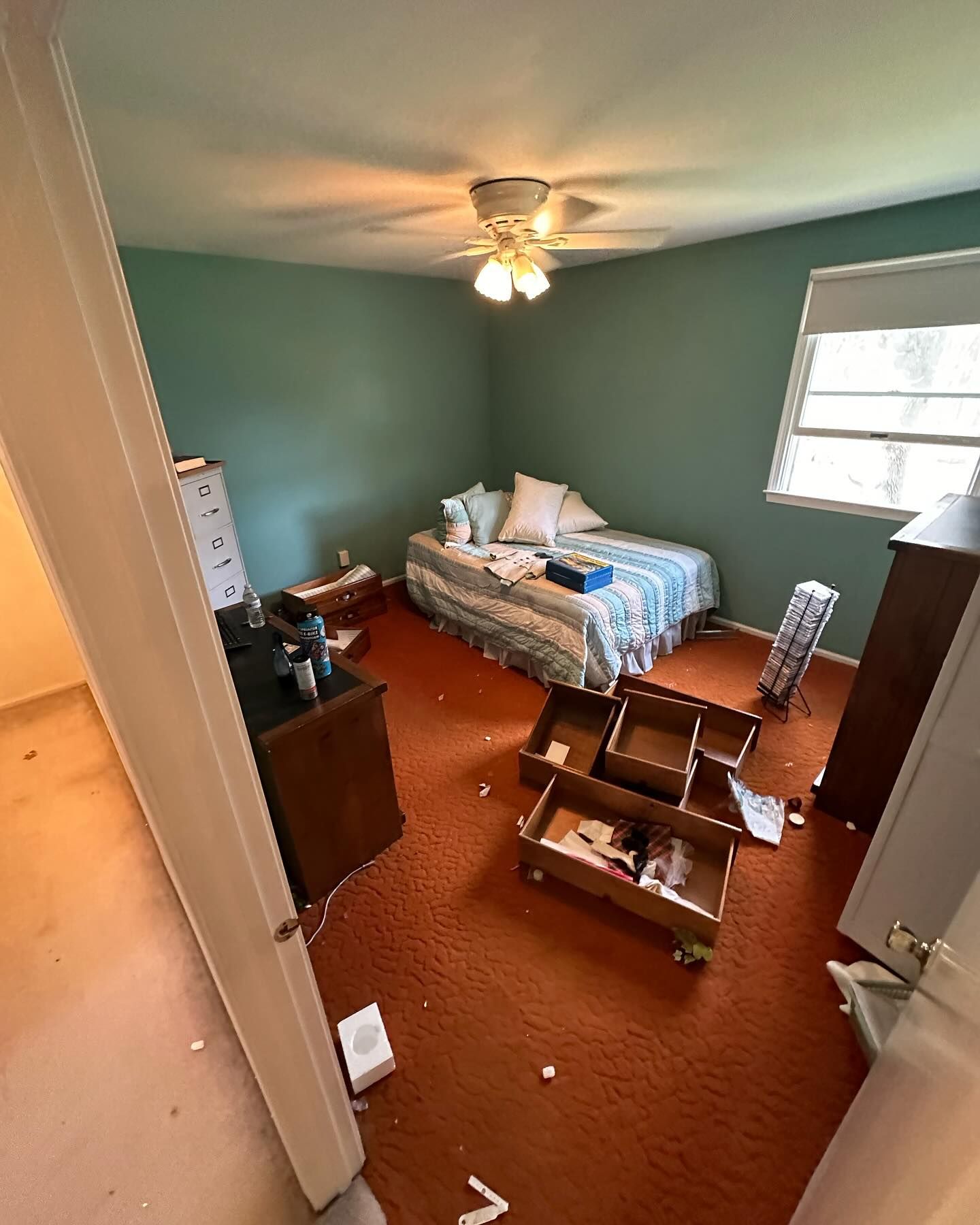 A bedroom with a bed, dresser, drawers and a ceiling fan