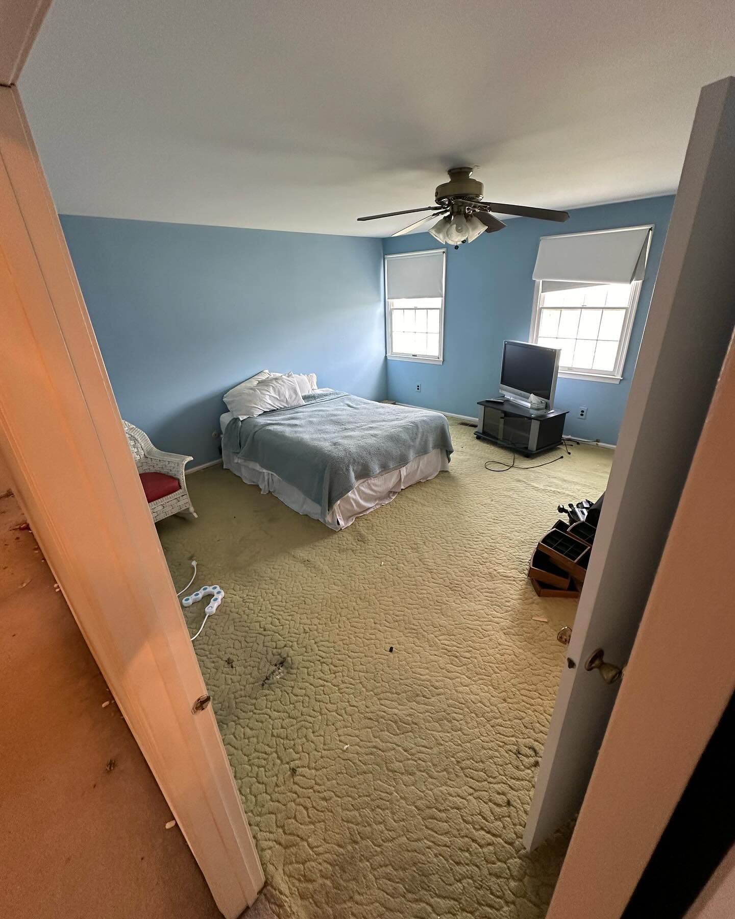 A bedroom with a bed a television and a ceiling fan