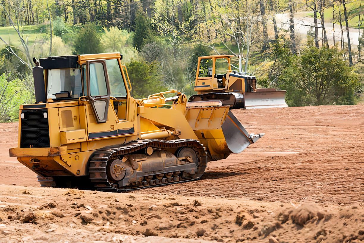 Two bulldozers are working in a dirt field