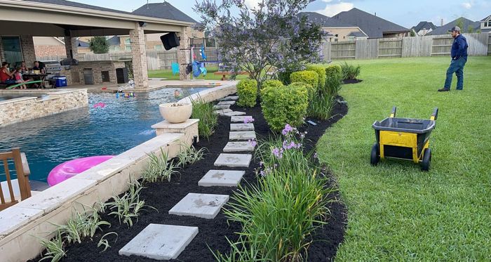 A man is standing in a backyard next to a pool.