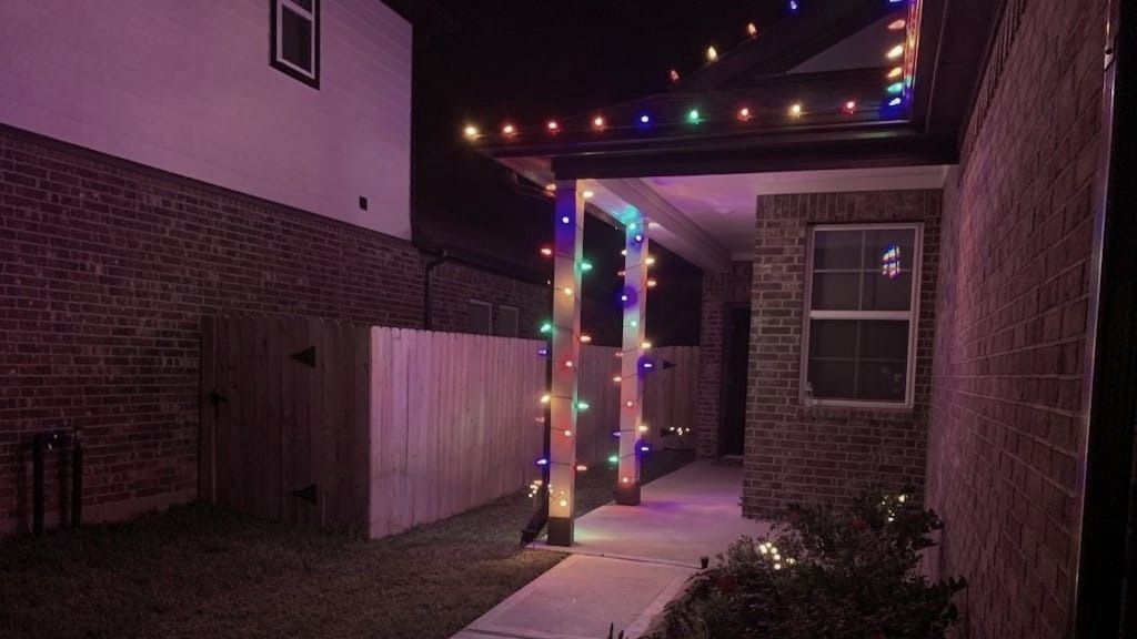 A house with christmas lights on the porch at night.